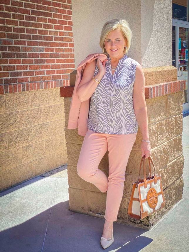 Fashion Blogger 50 Is Not Old is wearing a zebra print top with a pair of blush jeggings and carrying a Tory Burch tote 