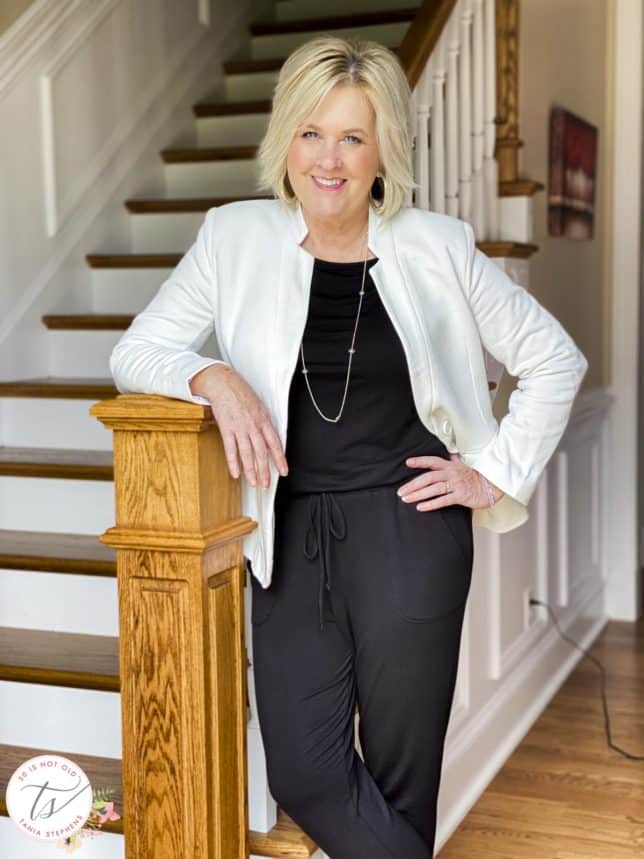 Fashion Blogger 50 Is Not Old is wearing a black jumpsuit and a white notched collar blazer from Gibsonlook with gold jewelry from Kendra Scott