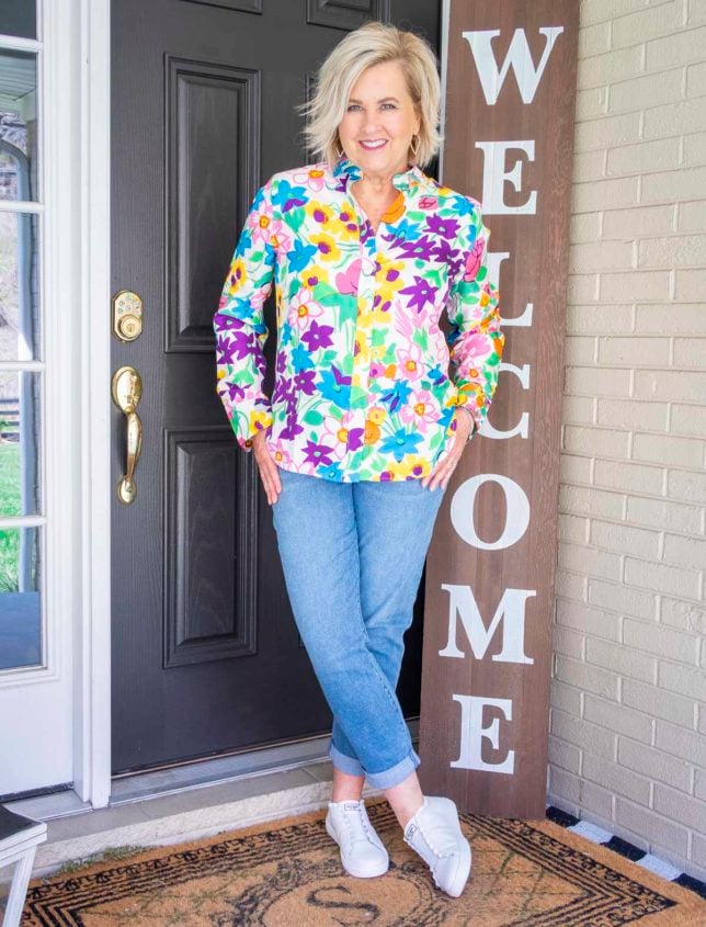 Fashion Blogger 50 Is not Old is making a bold statement in this brightly colored floral silk shirt, girlfriend jeans, and white leather sneakers from Kate Spade with ruffles