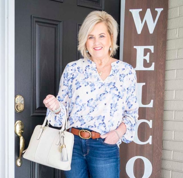 Fashion Blogger 50 Is Not Old is wearing a beautiful floral print top and carrying an ivory handbag
