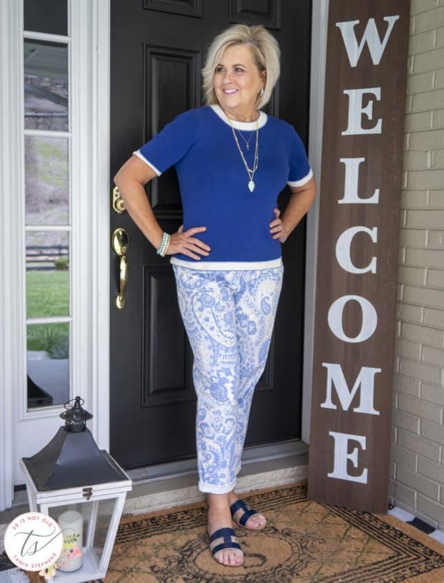 Fashion Blogger 50 Is Not Old is wearing a cobalt blue sweater, paisley pants, and a navy pair of sandals