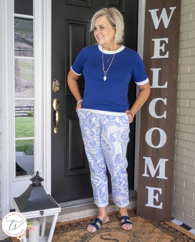Fashion Blogger 50 Is Not Old is wearing a cobalt blue sweater, blue and white paisley printed pants, and a navy pair of sandals