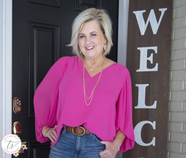Fashion Blogger 50 Is Not Old is wearing a v-neck pink blouse with gold jewelry