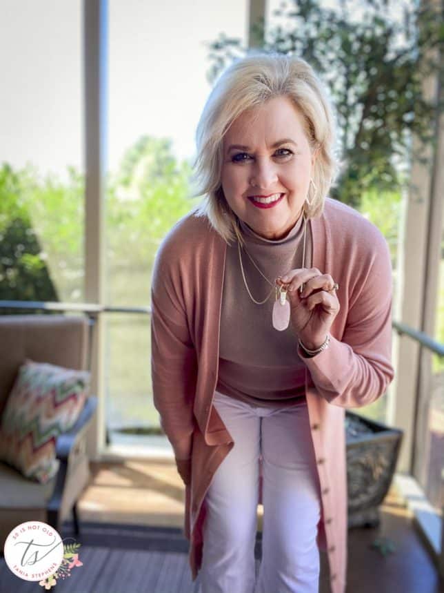 Fashion Blogger 50 Is Not Old is wearing a rose duster, a taupe shell, and showing her rose quartz necklace from Kendra Scott