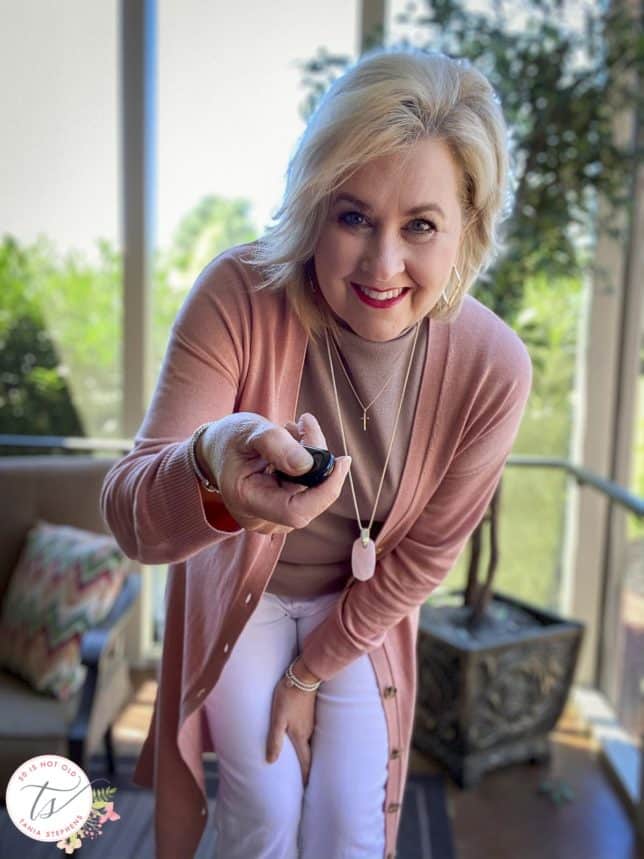 Fashion Blogger 50 Is Not Old is wearing a rose duster, a taupe shell, and showing her bluetooth clicker