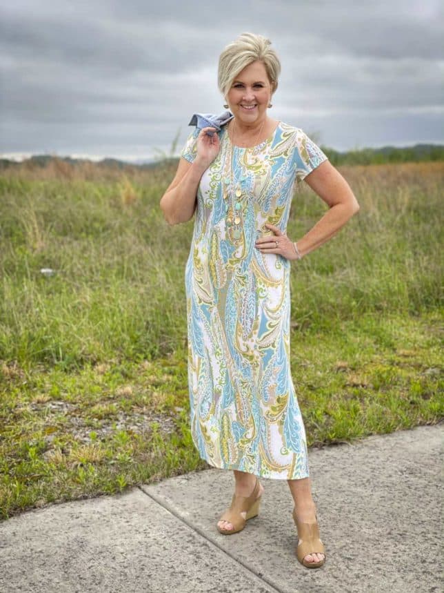 Fashion Blogger 50 Is Not Old has a denim jacket thrown over her shoulder of a paisley print maxi dress