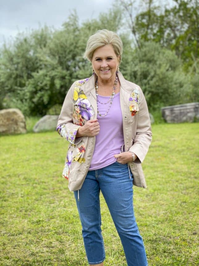 Fashion Blogger 50 Is Not Old is wearing a beautiful pale lavender tee with a floral satin utility jacket and cropped flare jeans
