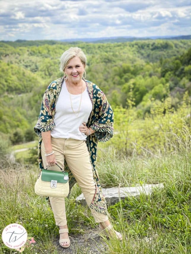 Fashion Blogger 50 Is Not Old is wearing a duster cardigan with a beige tank and pale gold jeans and mountains in the background
