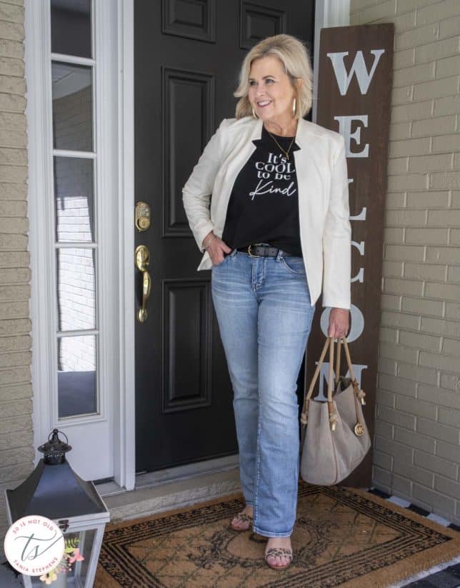 Fashion Blogger 50 Is Not Old is wearing a black and white graphic t-shirt with a white blazer, light jeans, and leopard print heels
