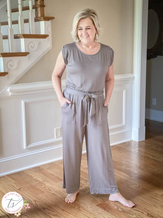 Fashion Blogger 50 Is Not Old is wearing a gray jumpsuit with an elastic waist and sash