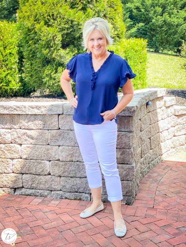Fashion Blogger 50 Is Not Old is wearing a navy ruffle v-neck top with white denim crops and white moccasin shoe from Michael Kors