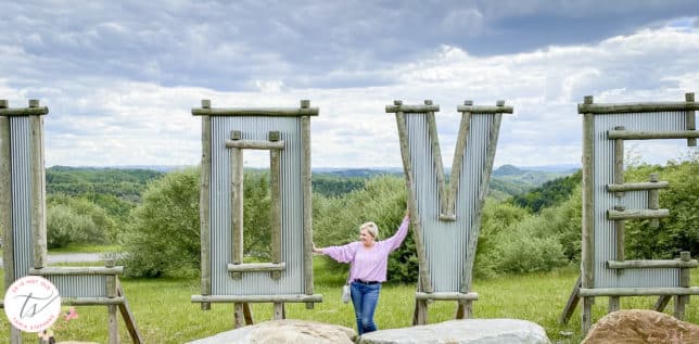 Fashion Blogger 50 Is Not Old is standing with a LOVE sign in a lilac top and jeans