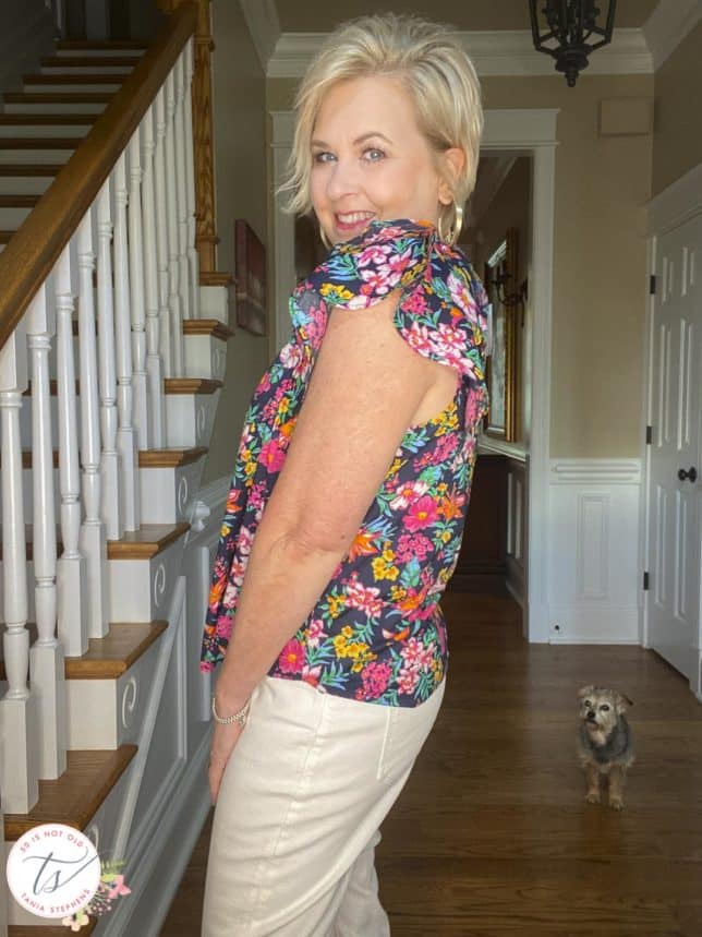 Fashion Blogger 50 Is Not Old is showing a side view of a colorful floral top with ruffled sleeves
