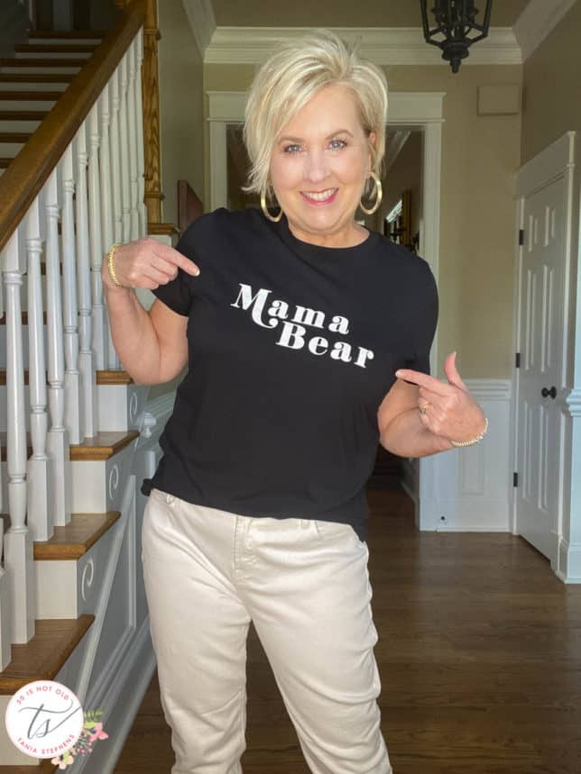 Fashion Blogger 50 Is Not Old is wearing a black and white Mama Bear graphic tee with white jeans