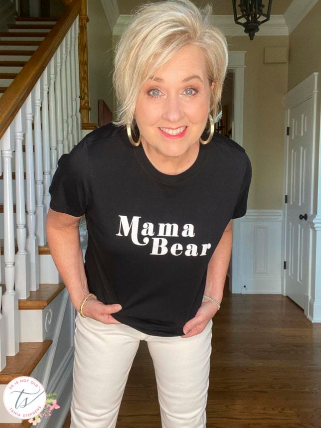 Fashion Blogger 50 Is Not Old is wearing a black and white Mama Bear graphic t-shirt with white jeans
