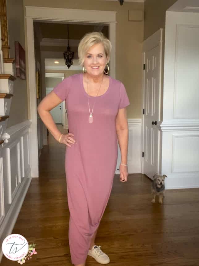 Fashion Blogger 50 Is Not Old is wearing a dusty rose long maxi dress that is tied up on one side with white Sperry sneakers