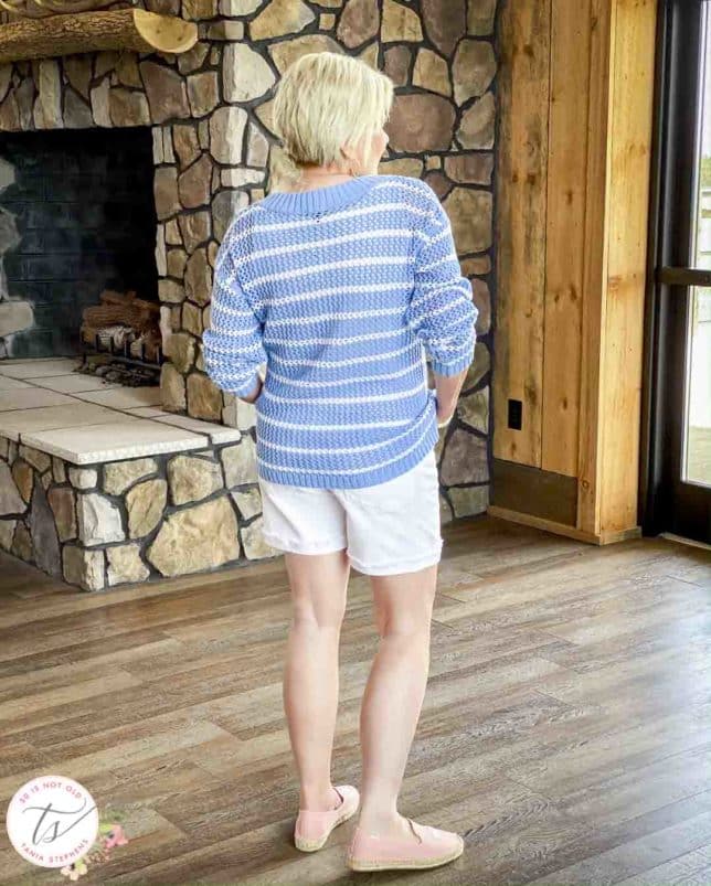 Fashion Blogger 50 Is Not Old is showing the back of a blue and white striped mesh sweater with white denim shorts and pink espadrilles