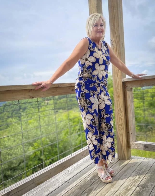 Fashion Blogger 50 Is Not Old is enjoying the view while wearing a big, bold blue print sleeveless tank and matching crop pants with espadrille wedge shoes