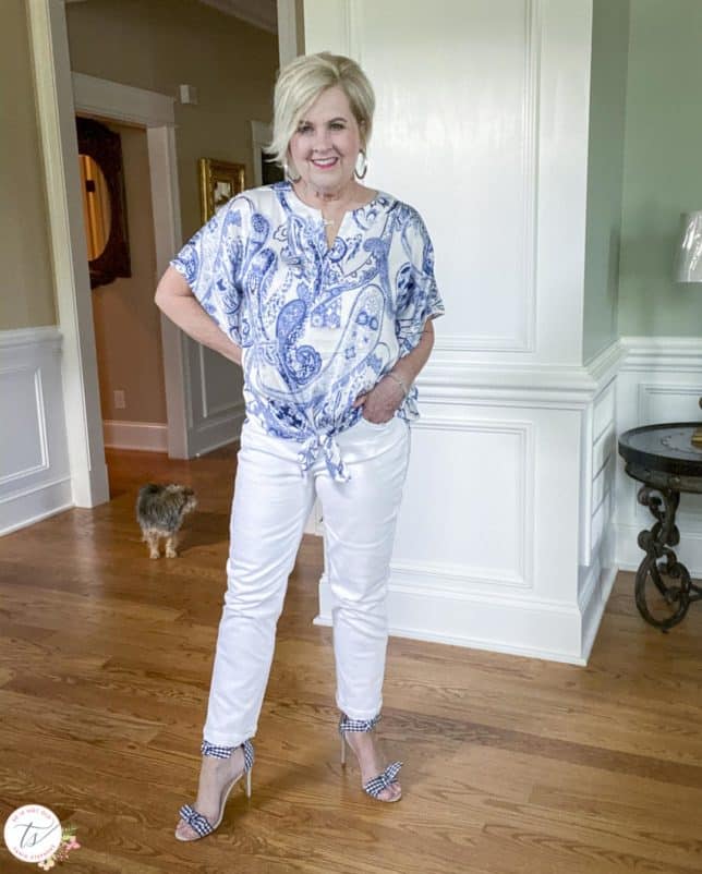 Fashion Blogger 50 Is Not Old is wearing a navy and white paisley tie-front top with white jeans and navy and white gingham heels