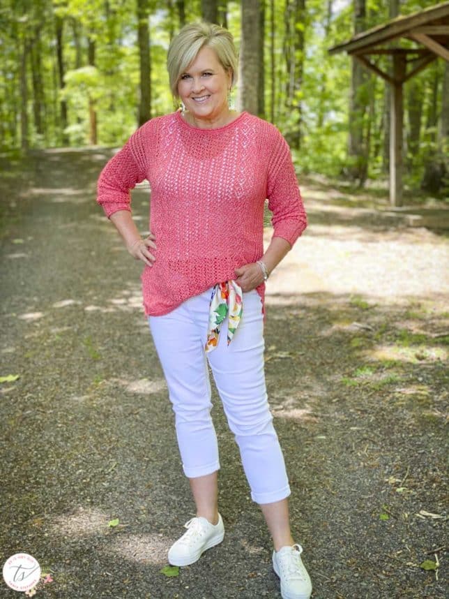 Fashion Blogger 50 Is Not Old is keeping cool in a coral open weave sweater, white crop jeans with a scarf for a belt, and Keds sneakers