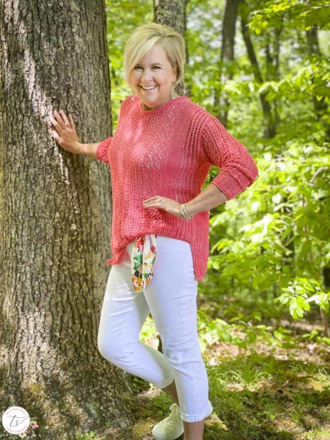 Fashion Blogger 50 Is Not Old is keeping cool in a coral open weave sweater, white crop jeans with a scarf for a belt, and white sneakers