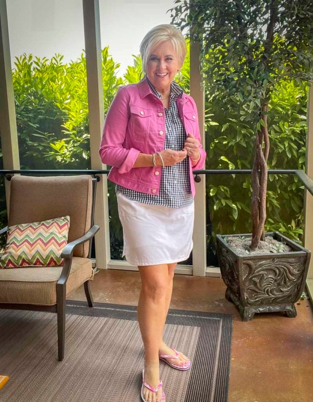 Fashion Blogger 50 Is Not Old is wearing an orchid jean jacket with a gingham button up sleeveless shirt with a white skort