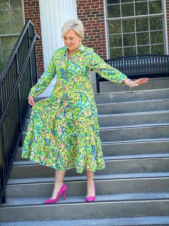 Fashion Blogger 50 Is Not Old is ready for an indoor wedding in this colorful tropical shirt dress with bright pink suede pumps