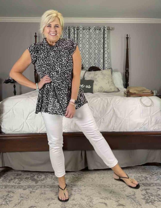 Fashion Blogger 50 Is Not Old is feeling sassy in a black and white polka dot top and white jeans with black thong sandals