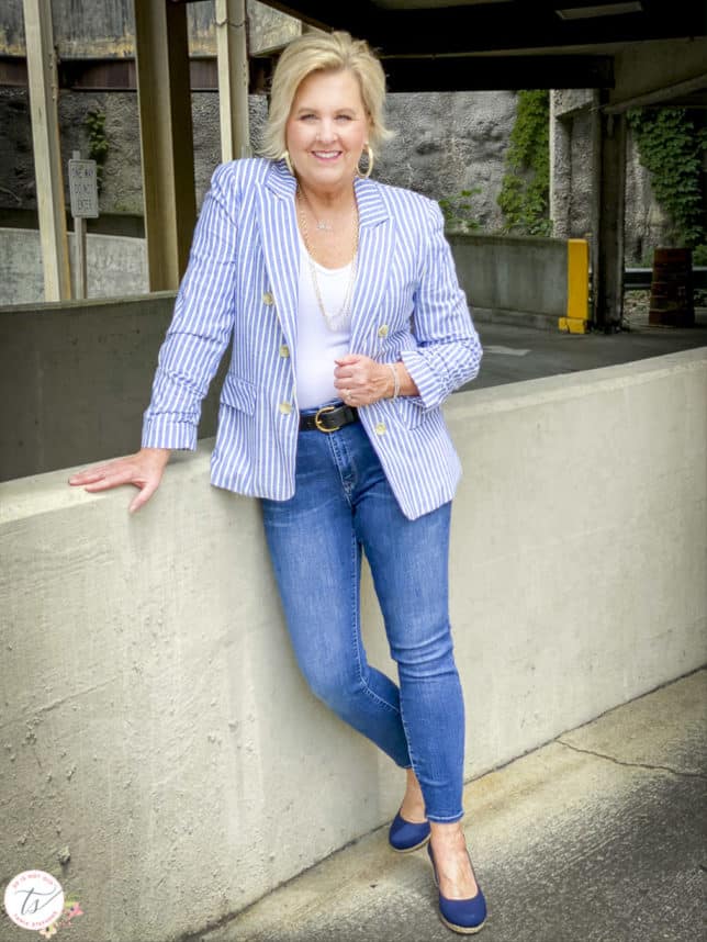 Fashion Blogger 50 Is Not Old is wearing a striped blue and white blazer, a white bodysuit, skinny jeans, and navy espadrilles