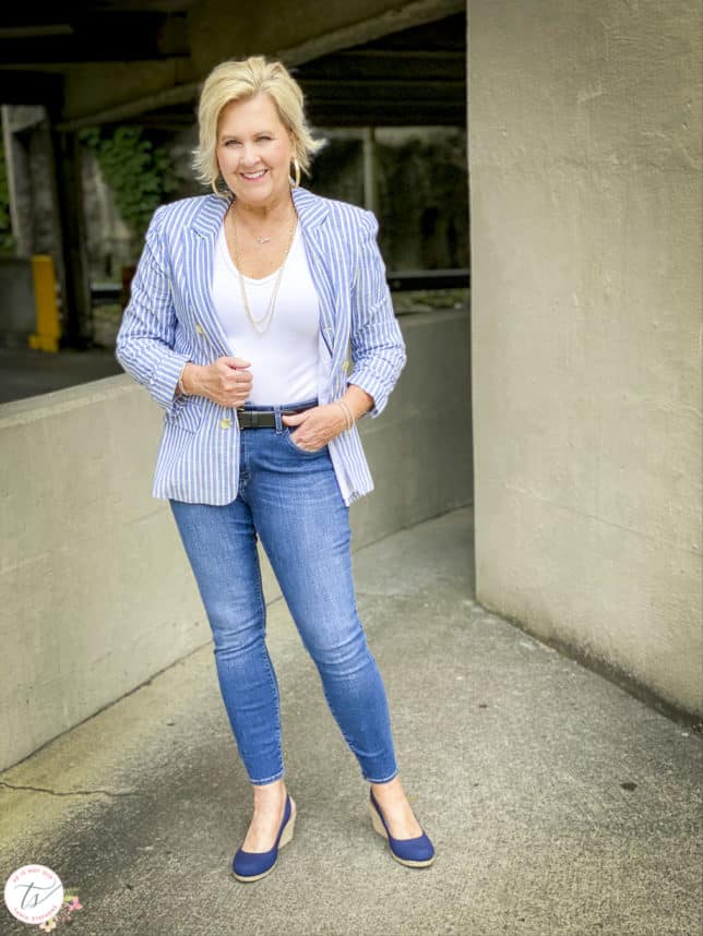 Fashion Blogger 50 Is Not Old is wearing a striped blue and white blazer, a white v-neck bodysuit, skinny jeans, and Vionic navy espadrilles