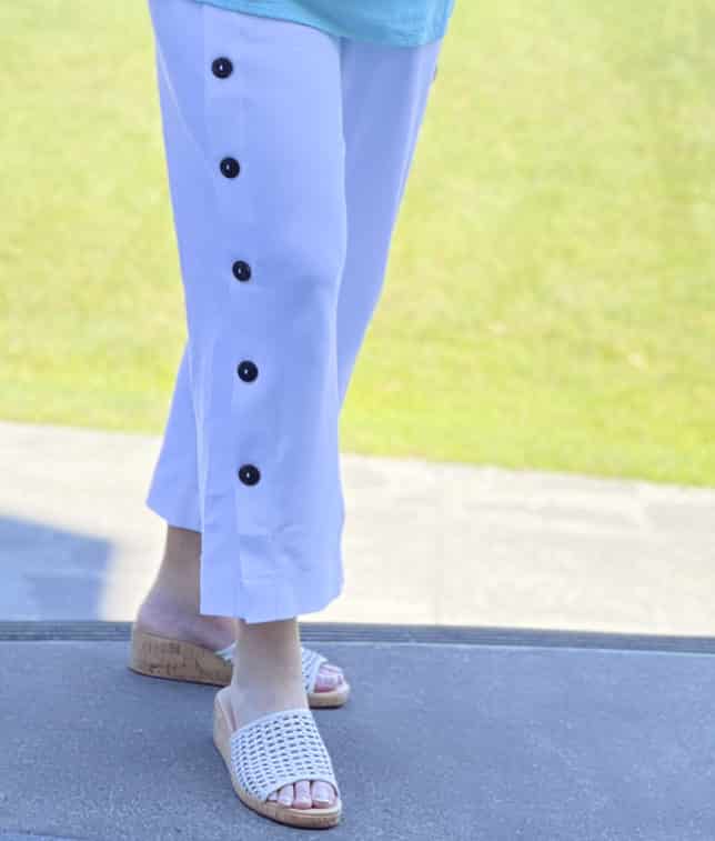 Fashion Blogger 50 Is Not Old is wearing white side button crop pants and slides