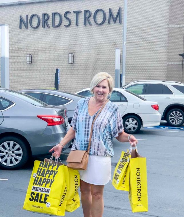 Fashion Blogger 50 Is Not Old is at a Nordstrom store with all of her purchases in yellow bags