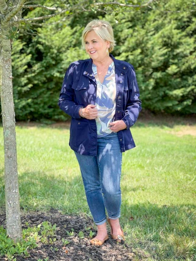 Fashion Blogger 50 Is Not Old is wearing a v-neck long sleeve top with cuffed jeans, a navy utility jacket, and flats by Tory Burch