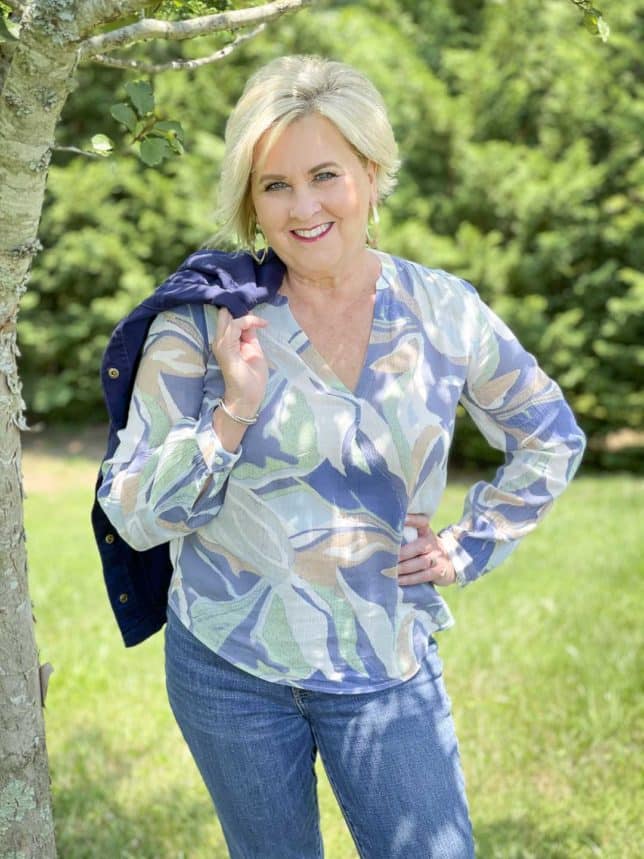 Fashion Blogger 50 Is Not Old is wearing a v-neck long sleeve top with a jacket thrown over her shoulder