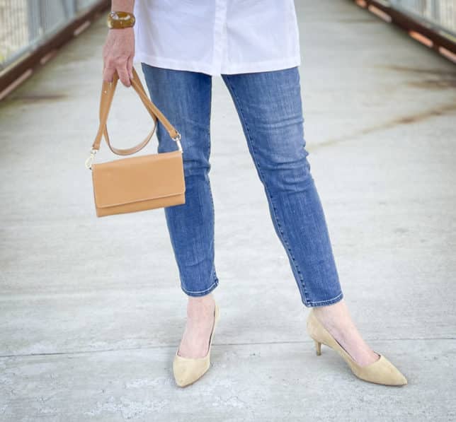 Over 40 Fashion Blogger, Tania Stephens, is wearing ankle length jeans, neutral heels, and carrying a camel crossbody wallet
