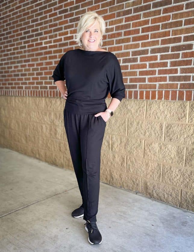 Over 40 Fashion Blogger, Tania Stephens is styling a casual weekend outfit of a black boat-neck top and pin tucked black pants with black sneakers with leopard print