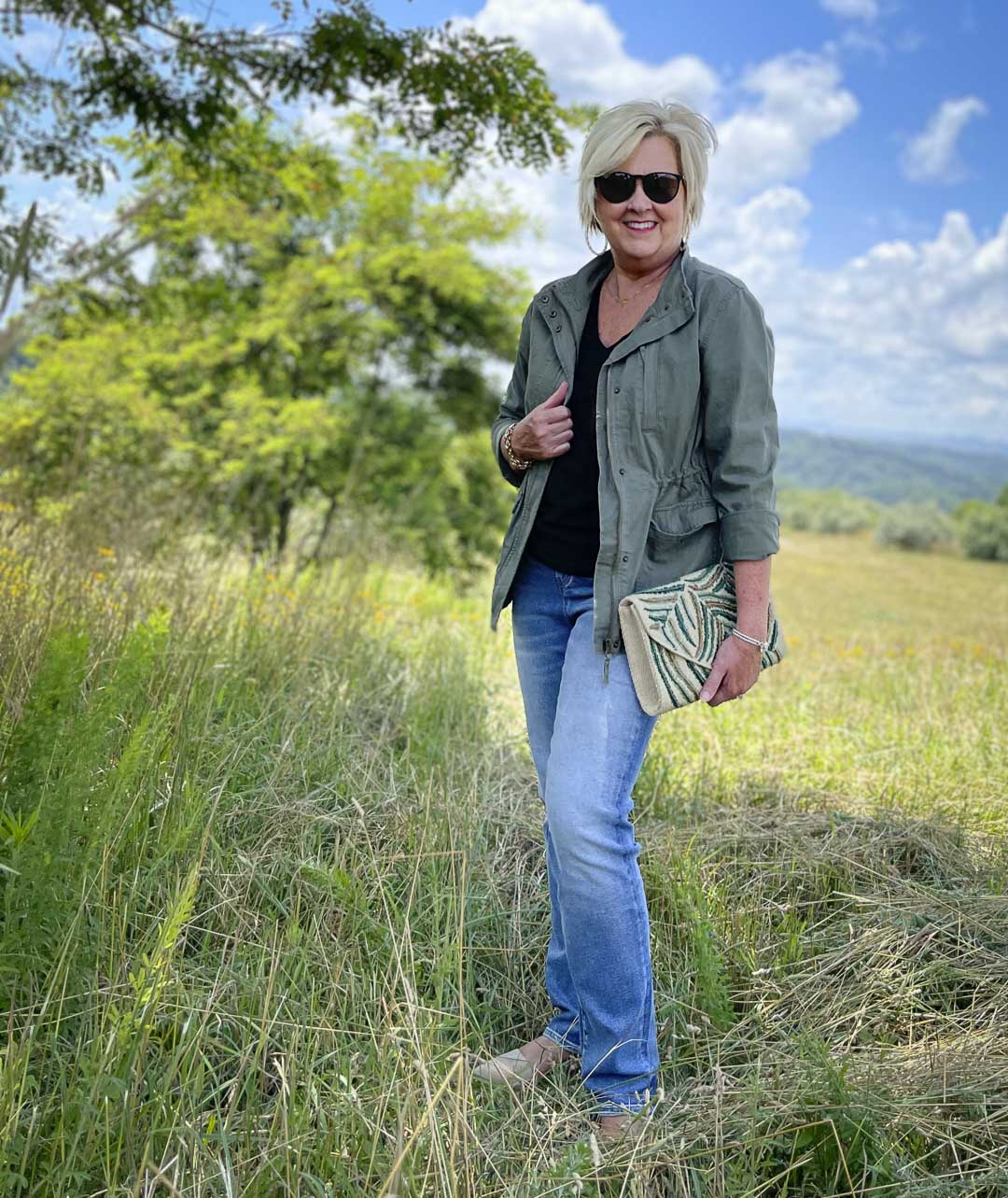 Fashion Blogger 50 Is Not Old is wearing black and olive together with jeans, Ray-Ban sunglasses, and an embroidered clutch