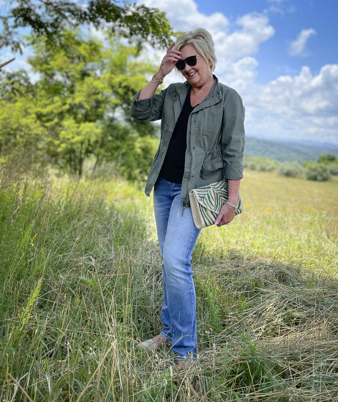 Fashion Blogger 50 Is Not Old is wearing black and olive together with jeans and an embroidered clutch