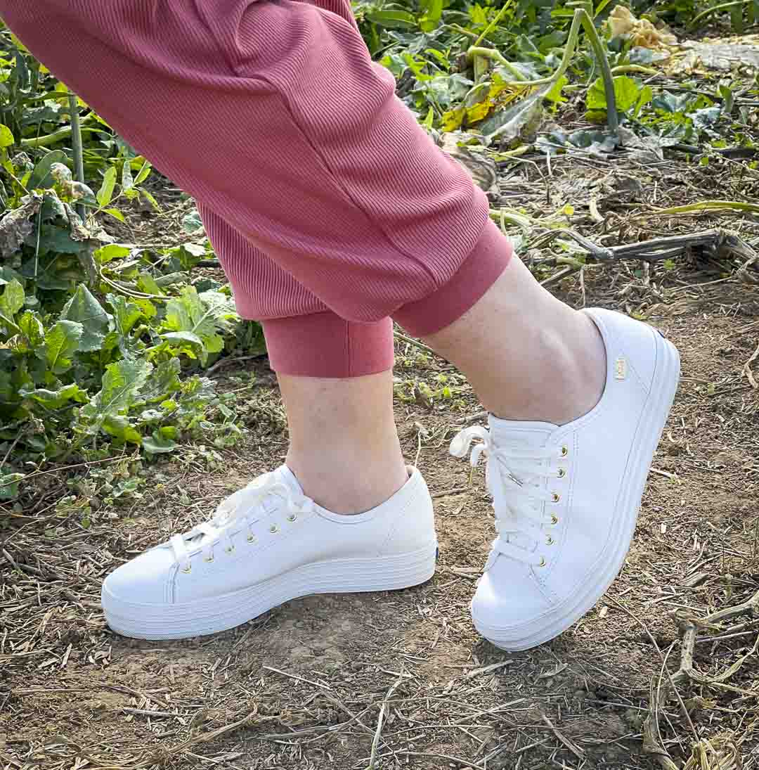 Over 40 Fashion Blogger, Tania Stephens is standing in a pumpkin patch in a pair of sneakers by Keds