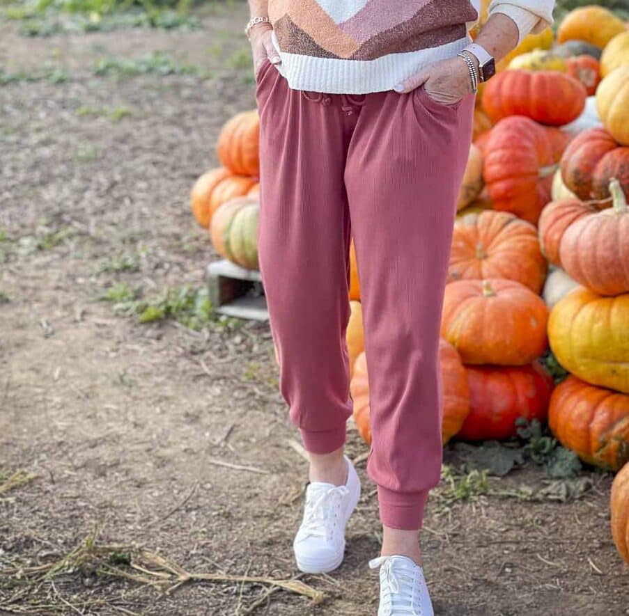 Over 40 Fashion Blogger, Tania Stephens is standing in a pumpkin patch in a Lou & Grey pair of joggers an Keds sneakers