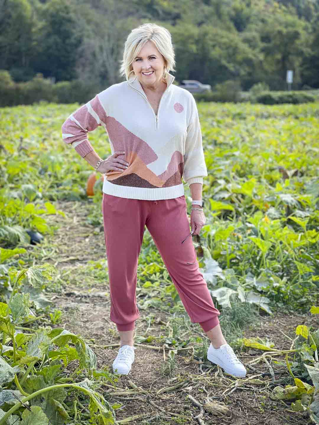 Over 40 Fashion Blogger, Tania Stephens is standing in a pumpkin patch in a Lou & Grey mountainside sweater and pair of joggers