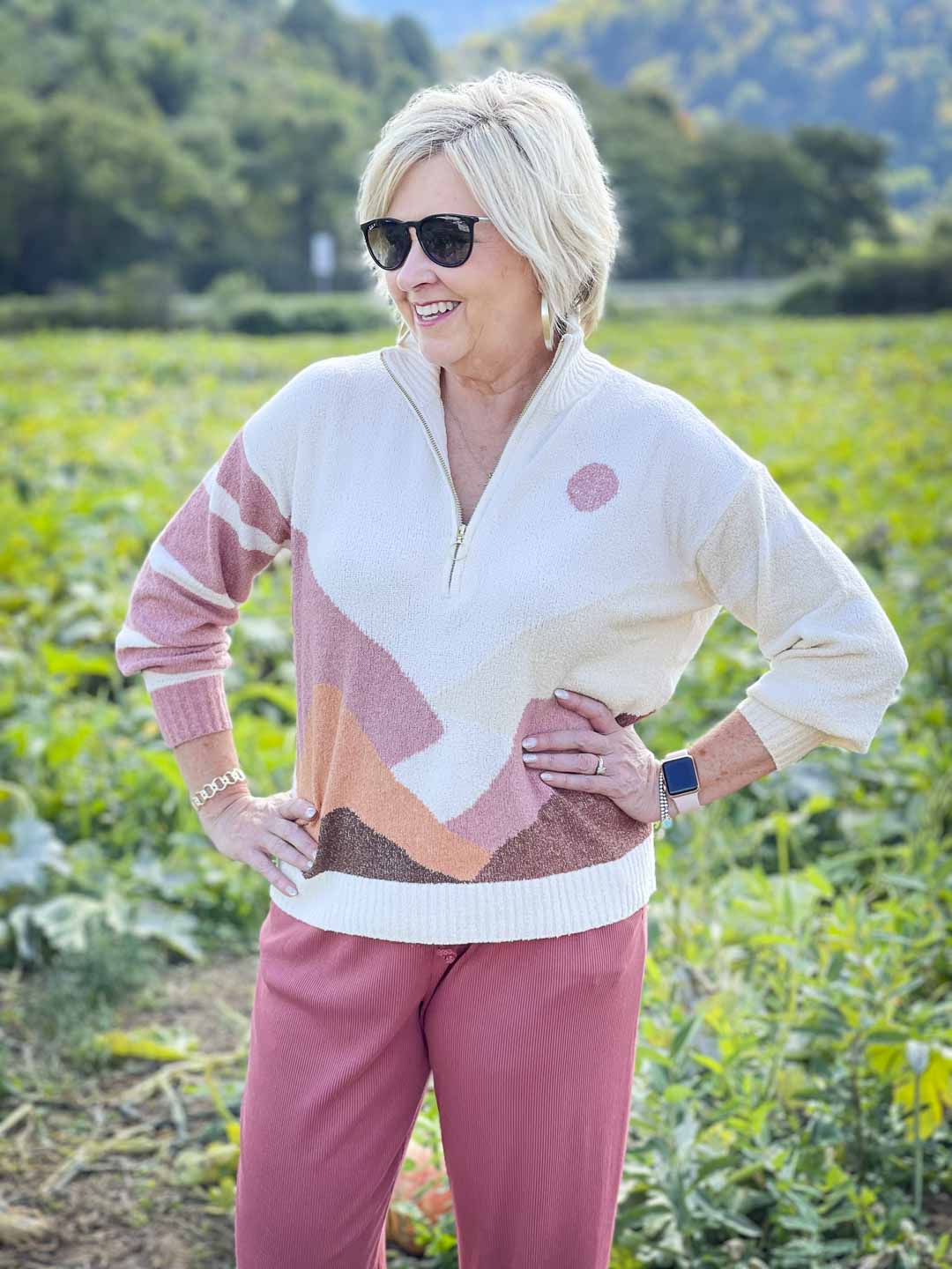 Over 40 Fashion Blogger, Tania Stephens is standing in a pumpkin patch in a Lou & Grey sweater and wearing a pair of sunglasses