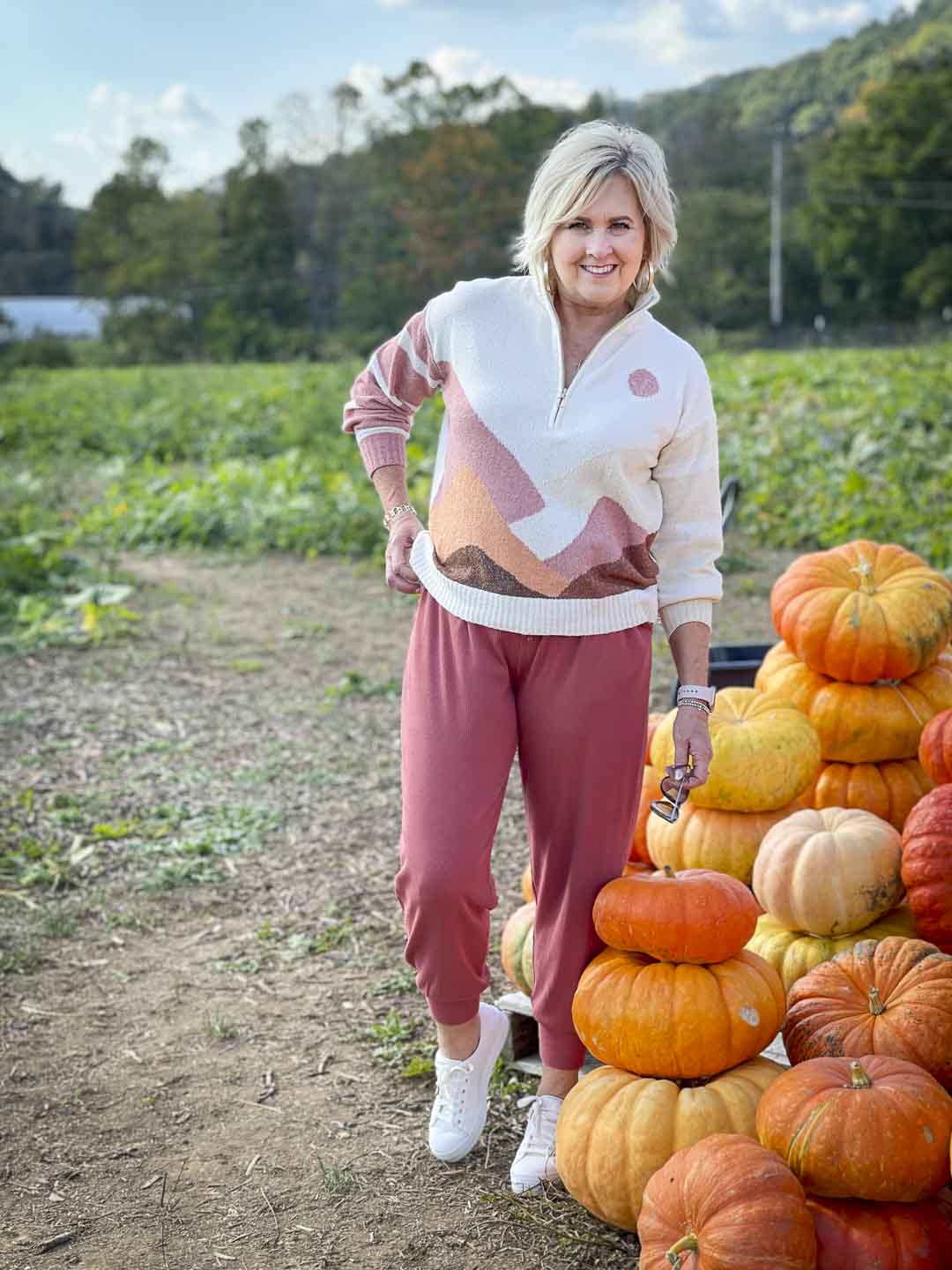 Over 40 Fashion Blogger, Tania Stephens is standing in a pumpkin patch in a Lou & Grey sweater and pair of joggers