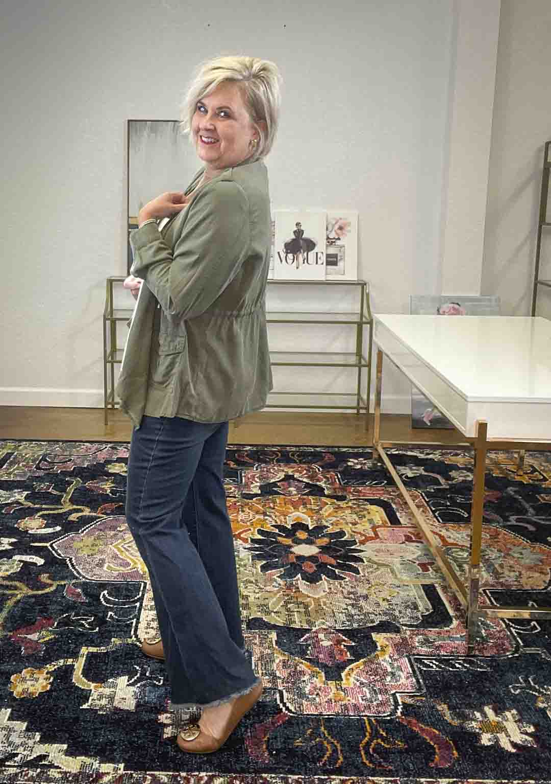 Over 40 Fashion Blogger, Tania Stephens, is styling an olive cargo jacket, a tan sweater, and flare jeans for fall from Target