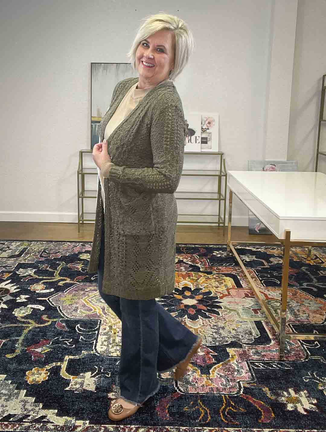 Over 40 Fashion Blogger, Tania Stephens, is styling an olive crochet duster, a camel sweater, and flare jeans for fall from Target