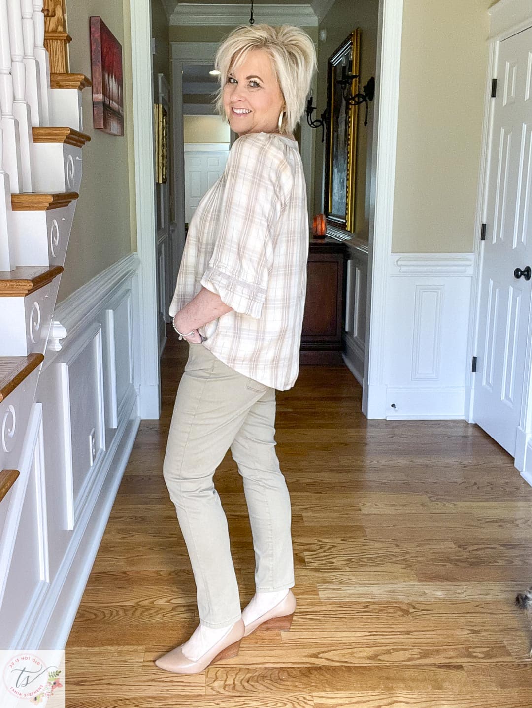 Over 40 fashion blogger, Tania Stephens, is wearing soft khaki straight-leg pants with a cream plaid peasant top and neutral wedge heels