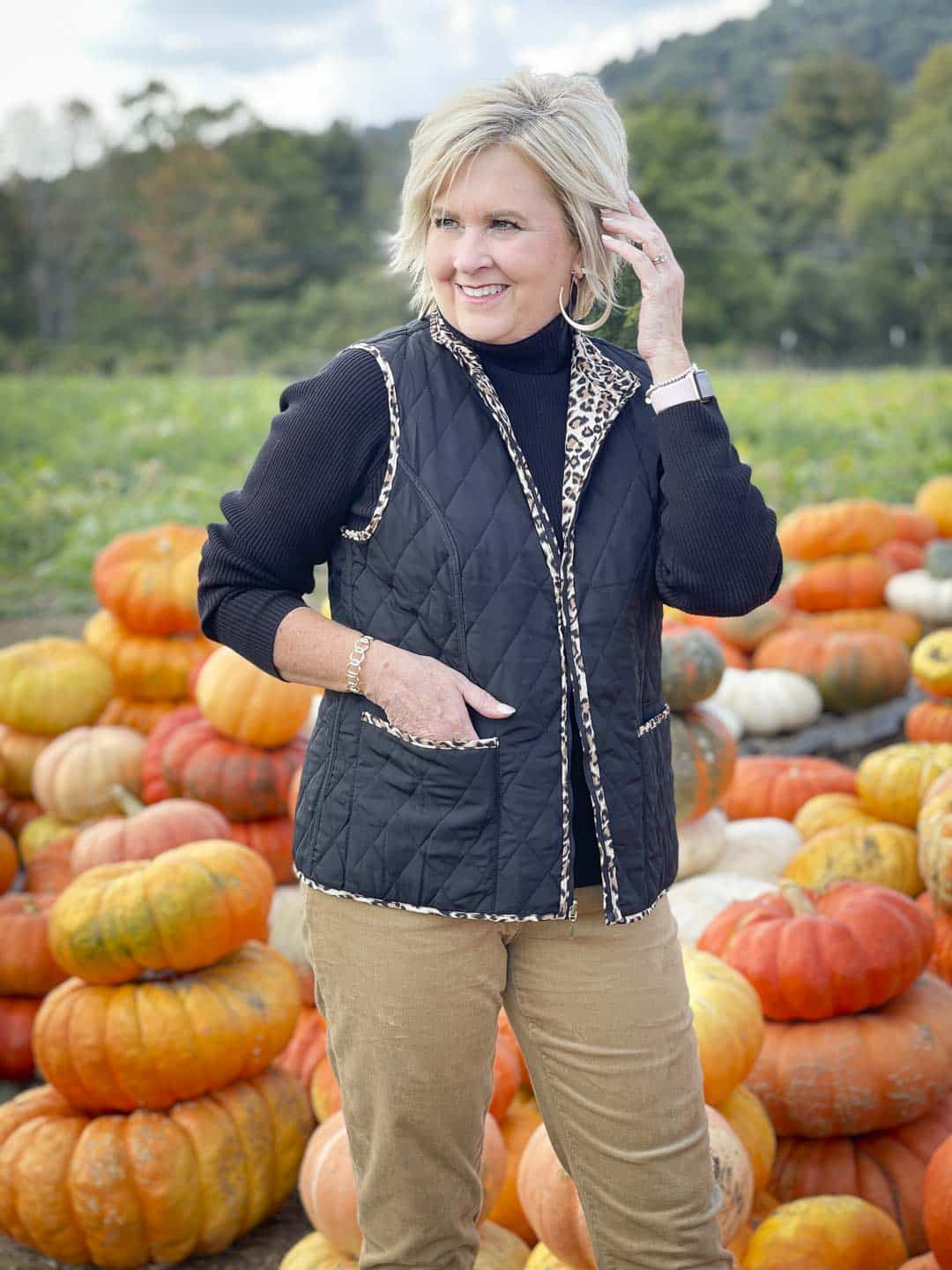 Over 40 Fashion Blogger, Tania Stephens, is in a pumpkin field wearing a reversible animal print vest
