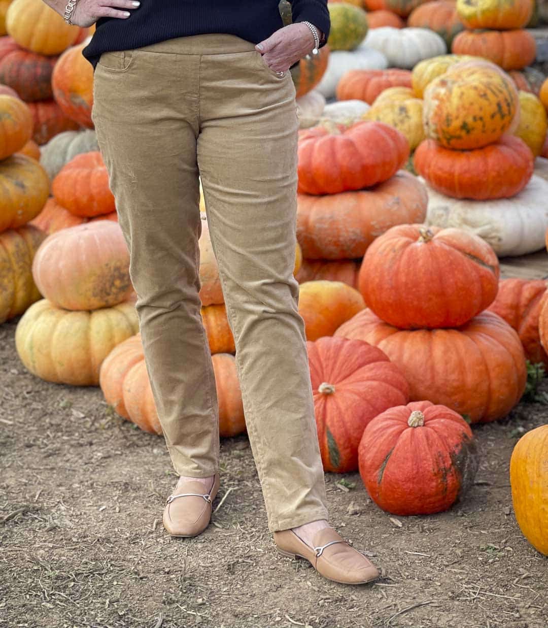Over 40 Fashion Blogger, Tania Stephens, is in a pumpkin field wearing camel corduroy pants