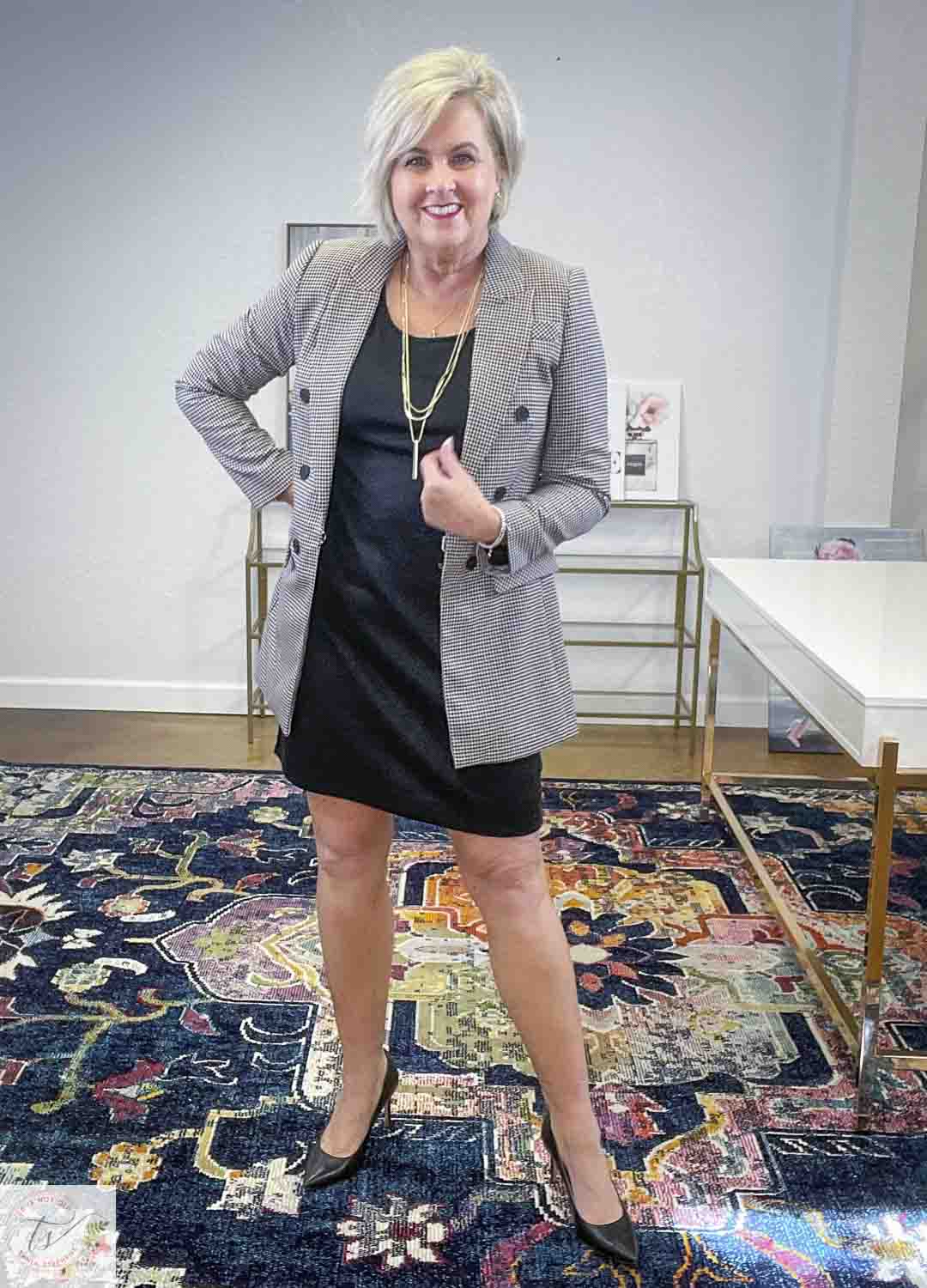 Over 40 Fashion Blogger, Tania Stephens, is wearing a little black dress, a double-breasted jacket, and black pumps
