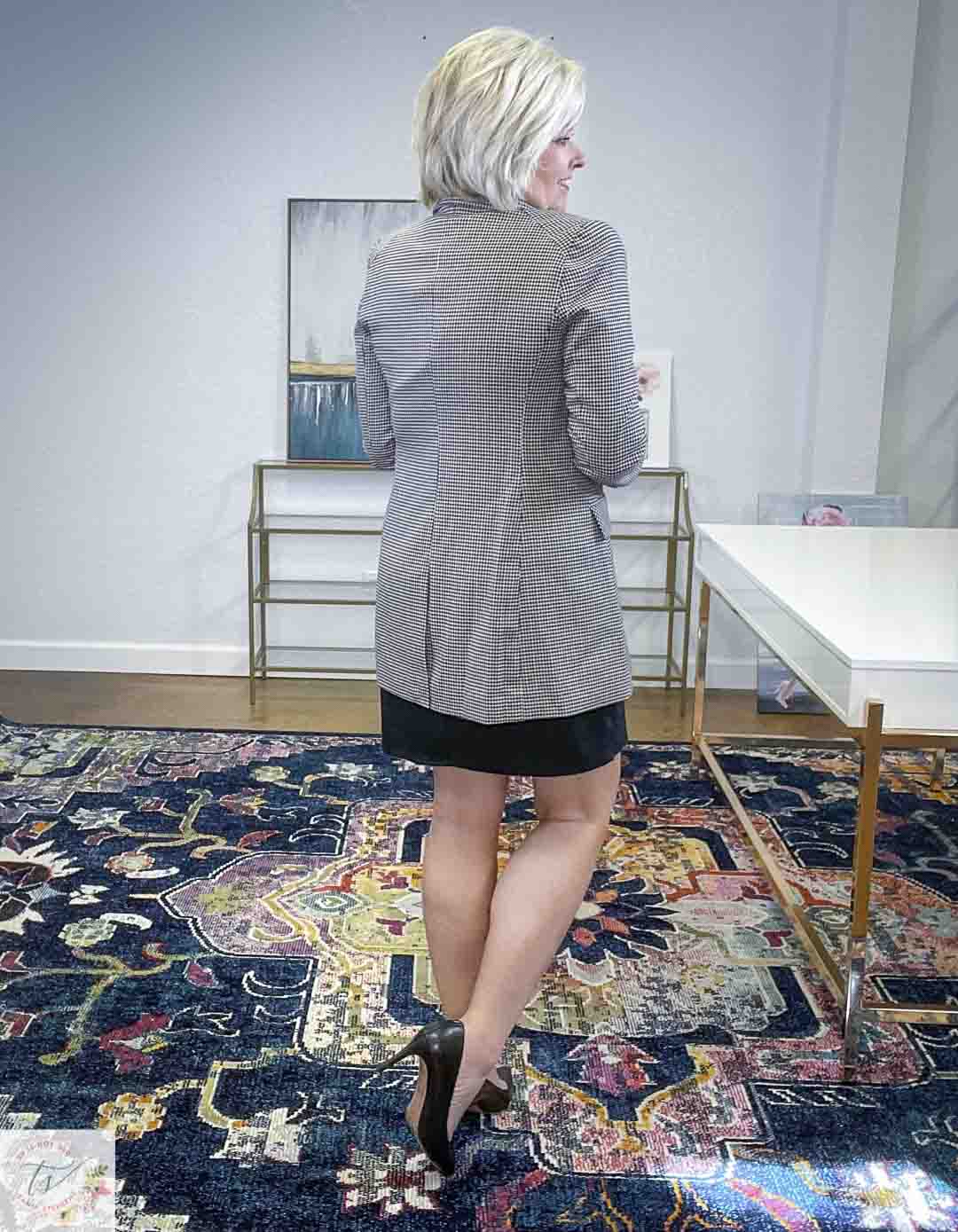 Over 40 Fashion Blogger, Tania Stephens, is showing the back of a little black dress, a checked blazer, and black pumps